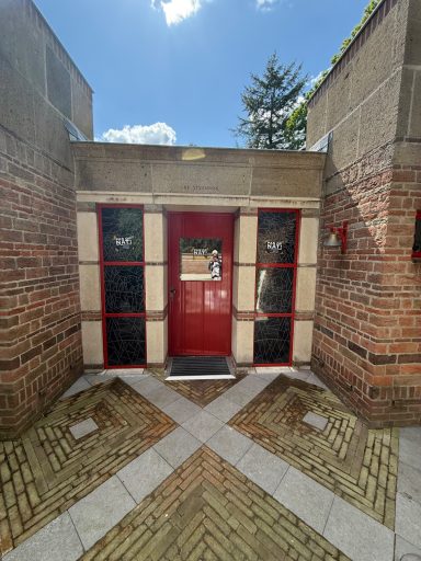 Heldere rode deur omringd door bakstenen muren en een betegeld pad.